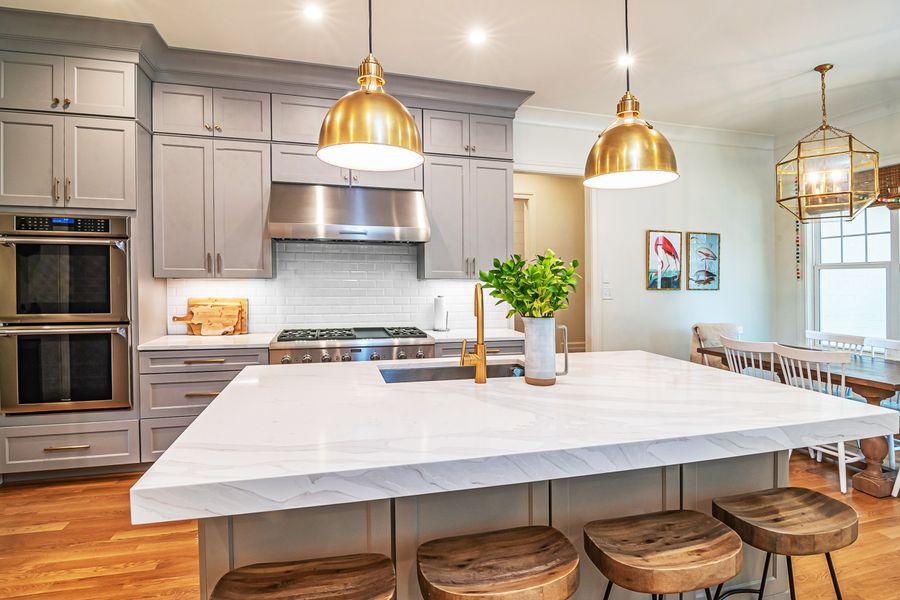Bright kitchen with a stone island and warm metal lighting
